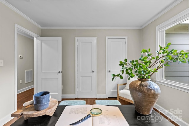 living area featuring crown molding, baseboards, wood finished floors, and visible vents