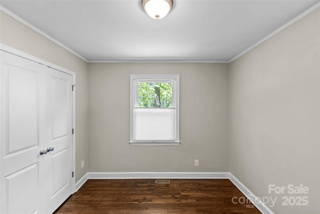 unfurnished bedroom featuring dark wood-style flooring, visible vents, crown molding, baseboards, and a closet