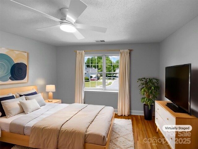 9830 Sandman Ln, Charlotte, NC 28216 - bedroom with light wood-style flooring, visible vents, a textured ceiling, and a ceiling fan