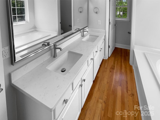 9830 Sandman Ln, Charlotte, NC 28216 - bathroom with a bath, wood finished floors, a sink, and double vanity