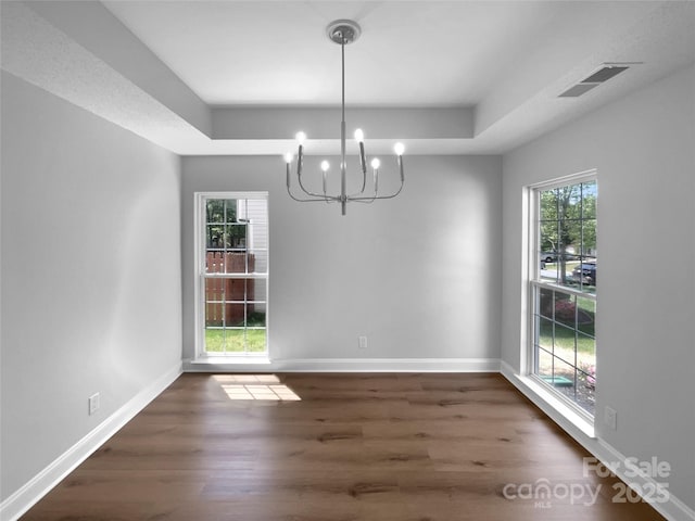 9830 Sandman Ln, Charlotte, NC 28216 - unfurnished dining area with dark wood-style flooring, baseboards, visible vents, a notable chandelier, and a raised ceiling