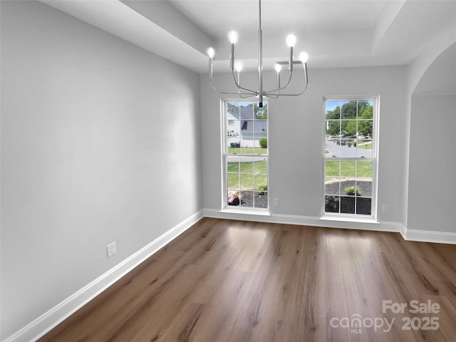 9830 Sandman Ln, Charlotte, NC 28216 - unfurnished dining area featuring arched walkways, baseboards, an inviting chandelier, and dark wood-style flooring