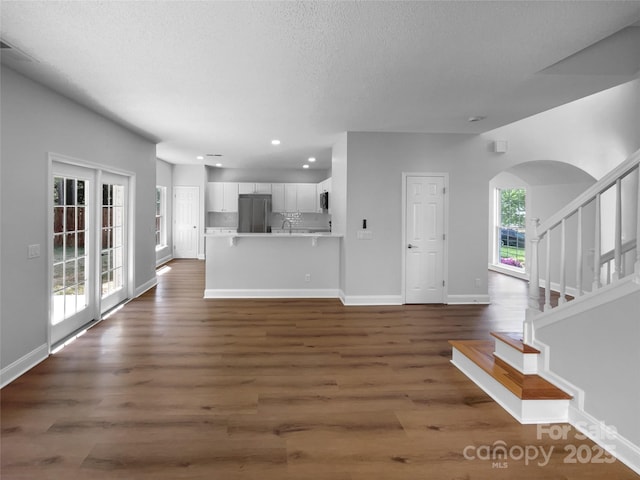 9830 Sandman Ln, Charlotte, NC 28216 - unfurnished living room with dark wood-style floors, baseboards, arched walkways, and recessed lighting