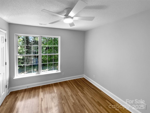 9830 Sandman Ln, Charlotte, NC 28216 - unfurnished room with a textured ceiling, wood finished floors, a healthy amount of sunlight, and ceiling fan