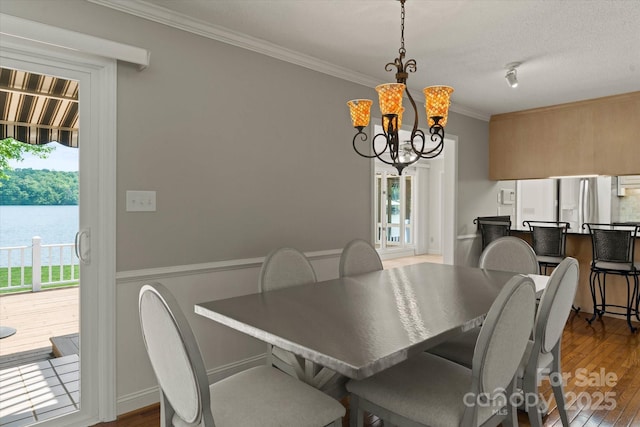dining space with an inviting chandelier, ornamental molding, and wood finished floors