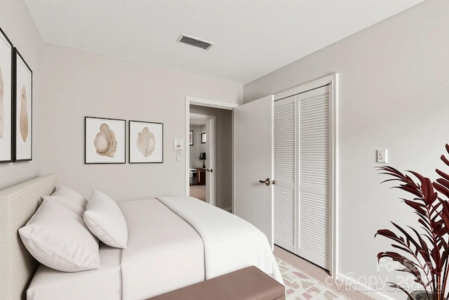 bedroom with visible vents, a closet, and light colored carpet