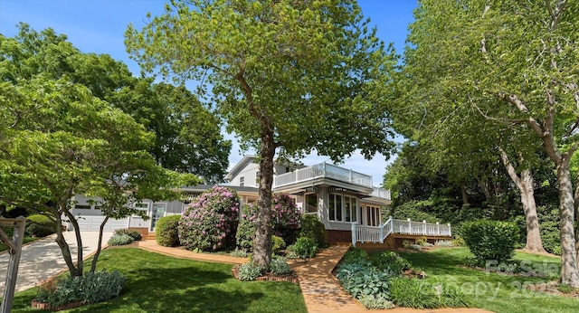 view of property exterior with a lawn, an attached garage, concrete driveway, and a balcony