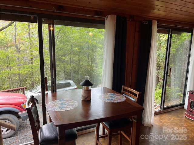 dining area with wooden ceiling and a forest view