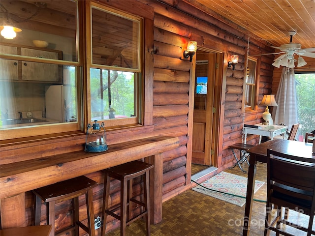 dining space featuring wooden ceiling, log walls, and ceiling fan