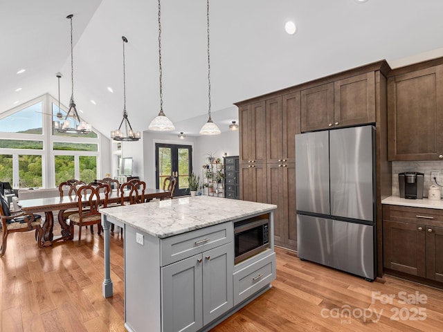 1810 Coopers Gap Rd, Mill Spring, NC 28756 - kitchen with light wood finished floors, appliances with stainless steel finishes, high vaulted ceiling, and a kitchen bar