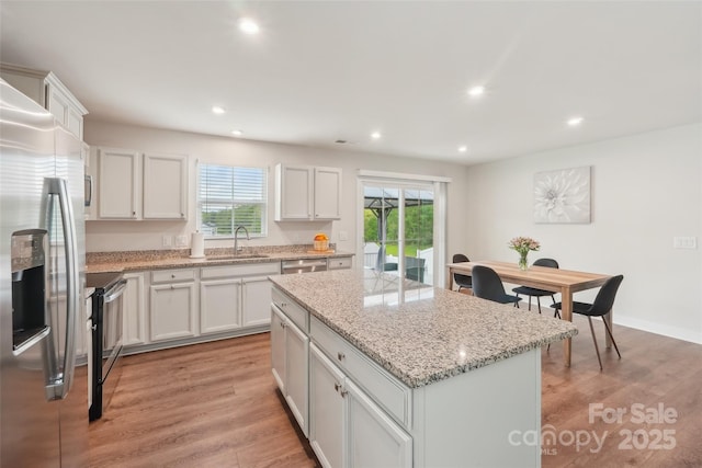 kitchen with appliances with stainless steel finishes, a center island, light wood-style flooring, and a sink