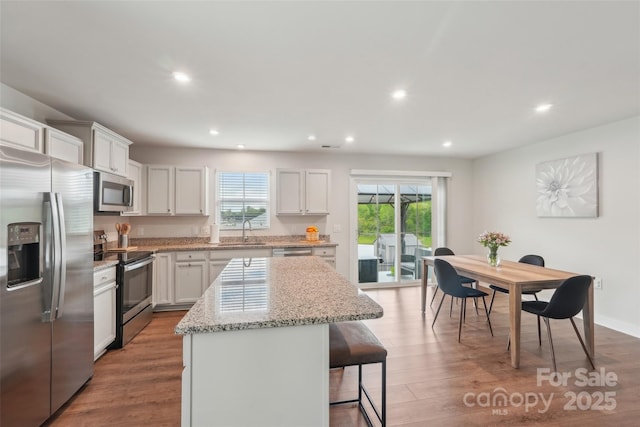 kitchen featuring a kitchen breakfast bar, a sink, stainless steel appliances, a center island, and recessed lighting