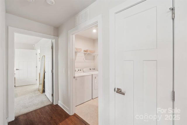 hall featuring baseboards, visible vents, wood finished floors, and washing machine and dryer