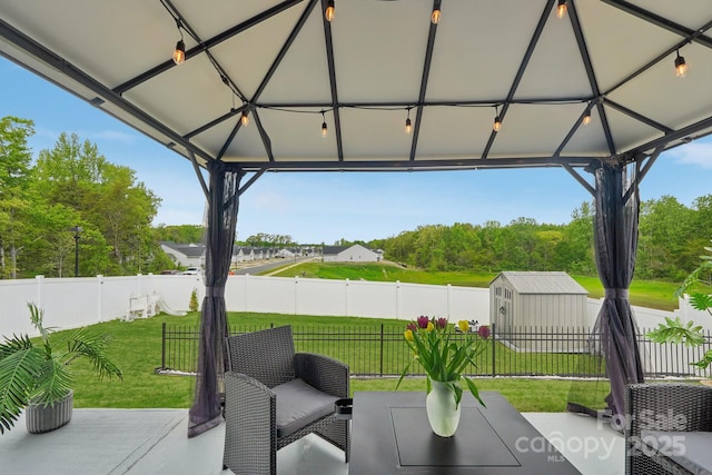 view of patio featuring a gazebo, a fenced backyard, a shed, and an outbuilding