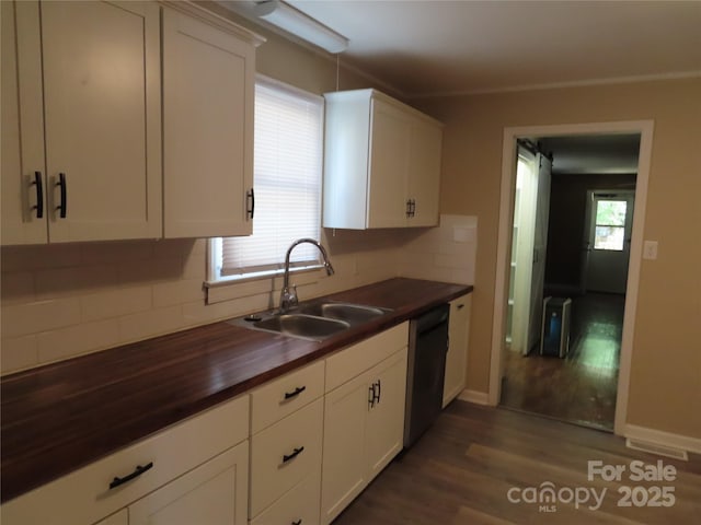 kitchen with wood counters, decorative backsplash, stainless steel dishwasher, a sink, and dark wood-style flooring