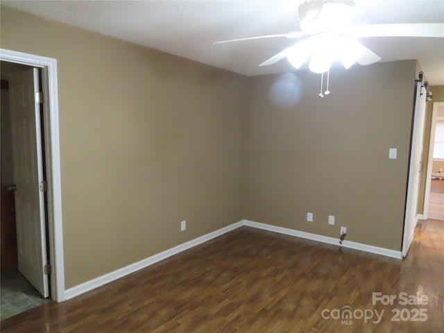 empty room featuring baseboards, ceiling fan, and dark wood-type flooring