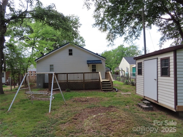 rear view of house with fence, an outdoor structure, a yard, and a wooden deck