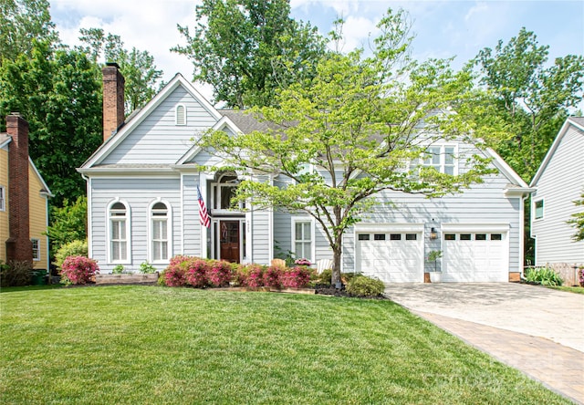 view of front facade featuring a chimney, a front lawn, concrete driveway, and an attached garage
