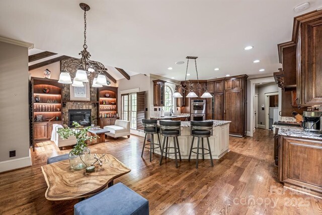 4600 Spicewood Dr, Charlotte, NC 28227 - interior space featuring wood finished floors, stainless steel double oven, light stone counters, a breakfast bar, and dark brown cabinets
