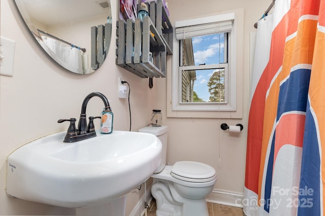 full bathroom featuring tile patterned flooring, curtained shower, a sink, baseboards, and toilet