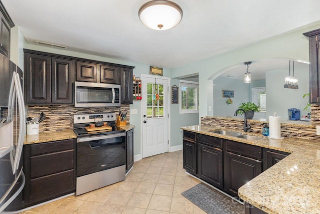 kitchen featuring a sink, arched walkways, stainless steel appliances, a wealth of natural light, and backsplash