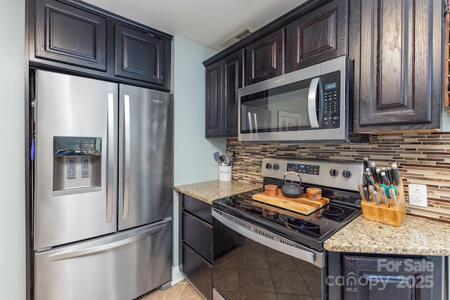 kitchen featuring light tile patterned floors, appliances with stainless steel finishes, decorative backsplash, and light stone counters