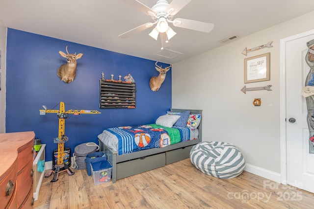 bedroom featuring a ceiling fan, baseboards, visible vents, and wood finished floors