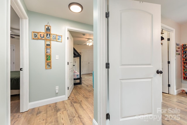 hallway featuring baseboards and light wood finished floors