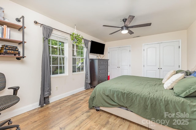bedroom with visible vents, multiple closets, wood finished floors, baseboards, and ceiling fan