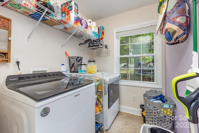 laundry area with washing machine and clothes dryer, laundry area, baseboards, and tile patterned flooring