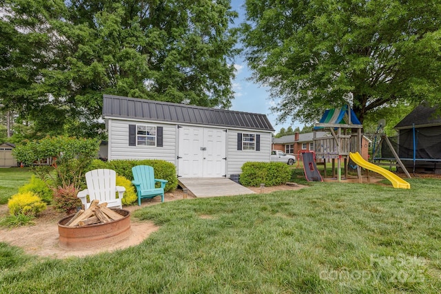 view of outbuilding featuring an outdoor structure, a playground, and a fire pit