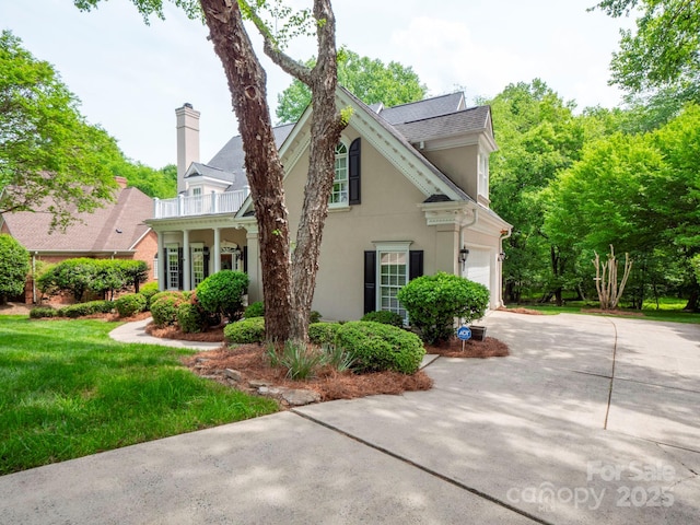 7716 Seton House Ln, Charlotte, NC 28277 - view of front of house with driveway, stucco siding, a garage, a chimney, and a balcony