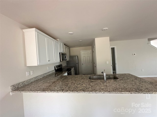 1345 Nia Rd, Charlotte, NC 28215 - kitchen with light stone counters, a sink, white cabinetry, a peninsula, and appliances with stainless steel finishes