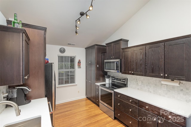 5804 Crosswinds Ct, Indian Trail, NC 28079 - kitchen featuring appliances with stainless steel finishes, a sink, dark brown cabinetry, decorative backsplash, and vaulted ceiling