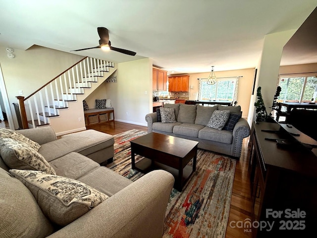 living room featuring a healthy amount of sunlight, baseboards, stairway, and dark wood-type flooring