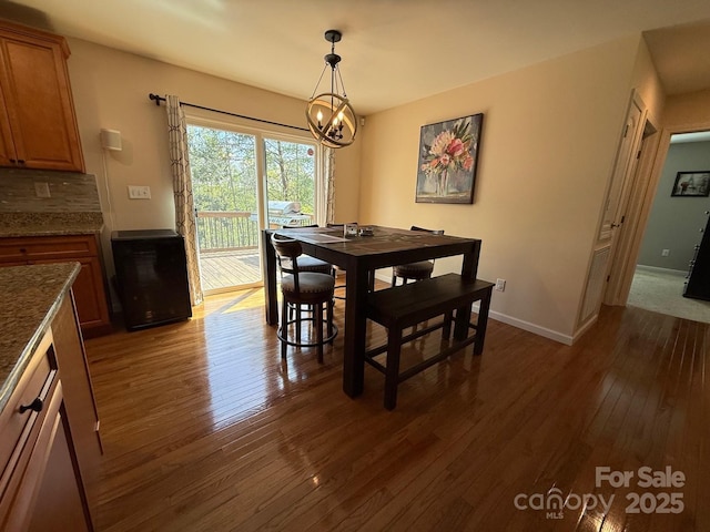 dining space with dark wood-type flooring, baseboards, and a chandelier
