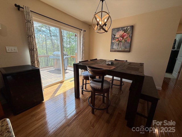 dining room featuring baseboards, wood finished floors, and a notable chandelier