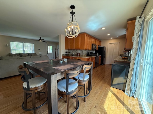 dining space with recessed lighting, ceiling fan with notable chandelier, and light wood finished floors
