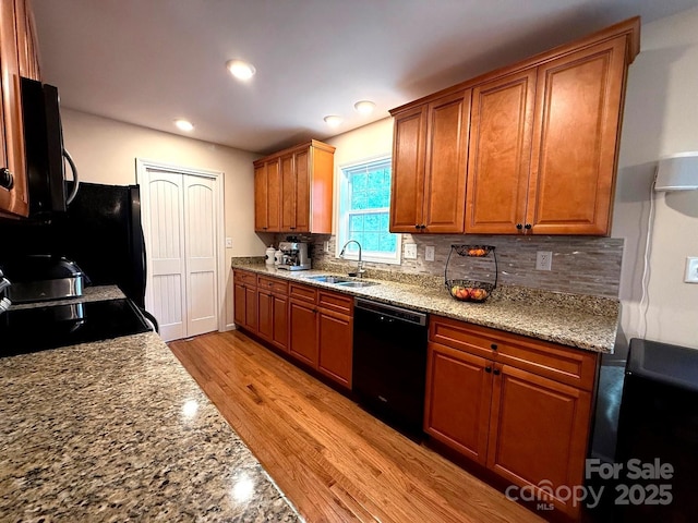 kitchen with brown cabinetry, a sink, black appliances, and tasteful backsplash