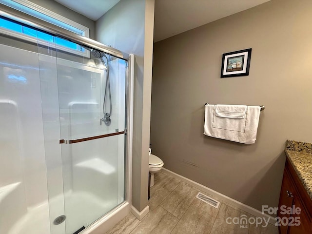bathroom with vanity, toilet, baseboards, a shower stall, and visible vents