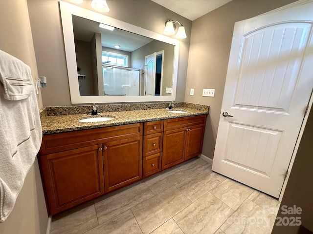 full bathroom featuring double vanity, baseboards, a shower stall, and a sink