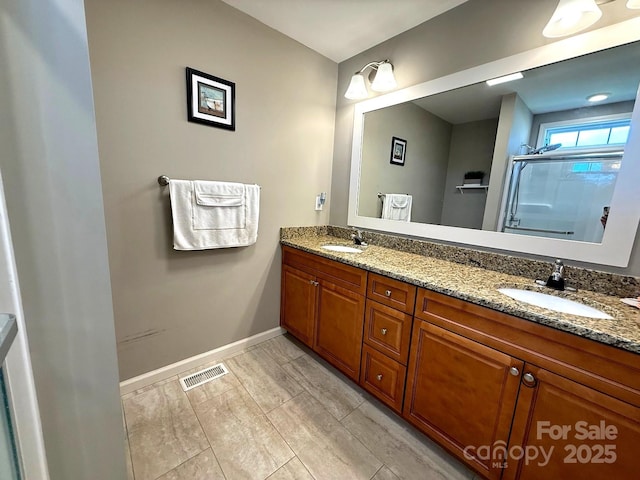 full bathroom featuring visible vents, a sink, baseboards, and a shower with shower door
