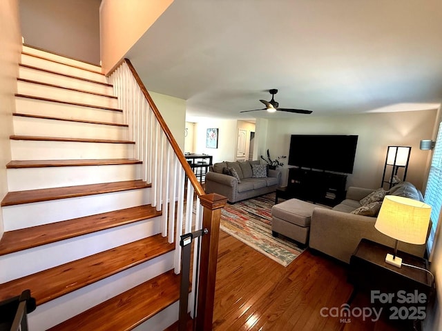 living area featuring ceiling fan, wood finished floors, and stairway