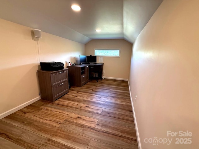 unfurnished office featuring baseboards, recessed lighting, wood finished floors, and vaulted ceiling