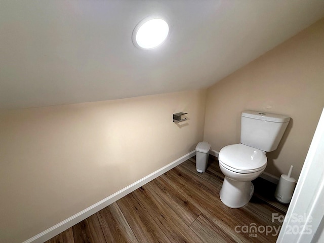bathroom featuring baseboards, toilet, wood finished floors, and lofted ceiling