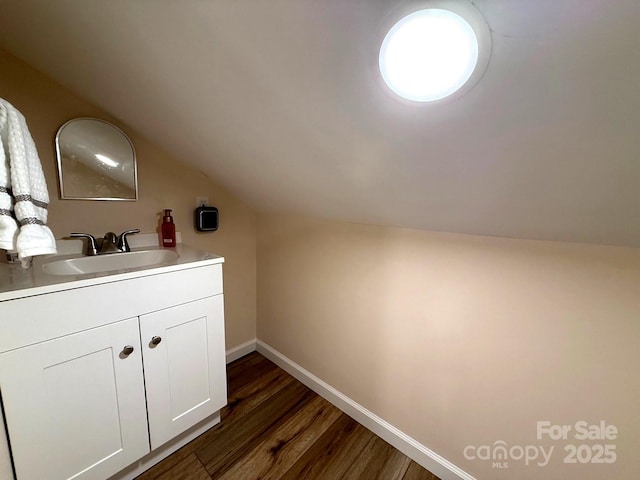 interior space with baseboards, a sink, dark wood-style flooring, and lofted ceiling