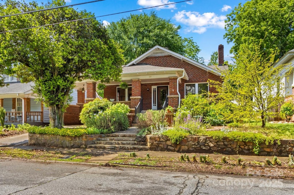 view of front facade featuring a porch, brick siding, and a chimney