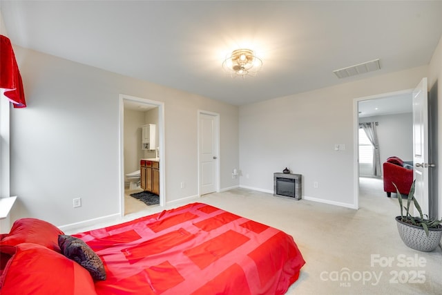carpeted bedroom featuring connected bathroom, baseboards, visible vents, and a wood stove