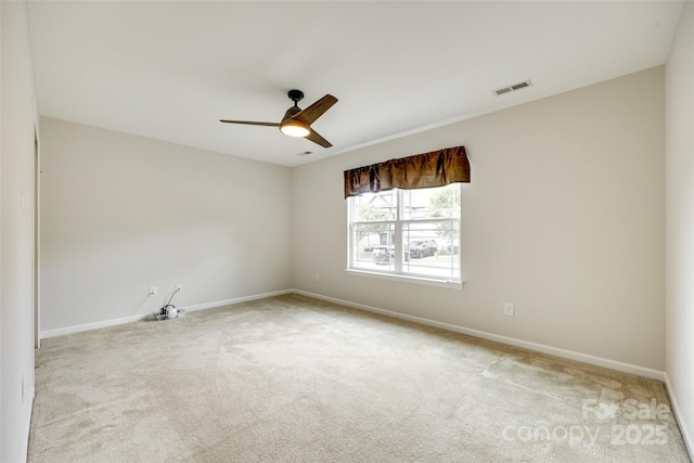 empty room with carpet floors, ceiling fan, baseboards, and visible vents