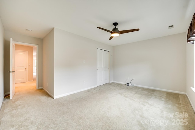 unfurnished bedroom with visible vents, a ceiling fan, baseboards, and light colored carpet